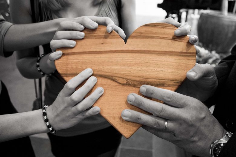 Hände halten ein Herz aus Holz